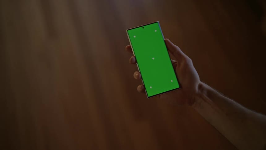 Man holding smartphone walks through a corridor
