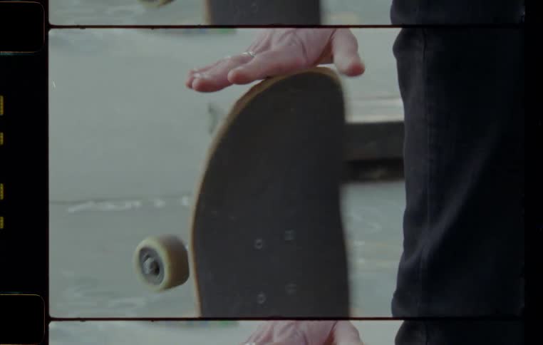 A person with rings on their fingers rotates a skateboard with their hand
