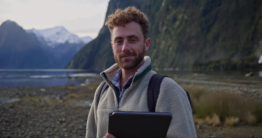 An explorer smiling and posing by the river bank