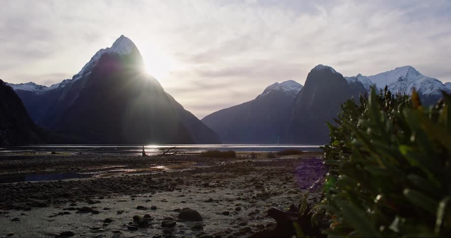 The sun shining behind a mountain peak in the morning giving light to the coastline during the winter