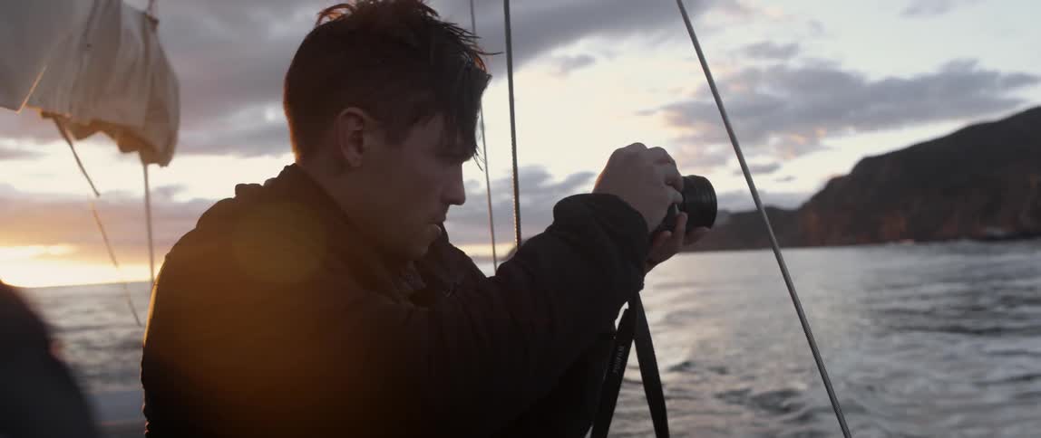 A man is taking photographs off the side of a boat