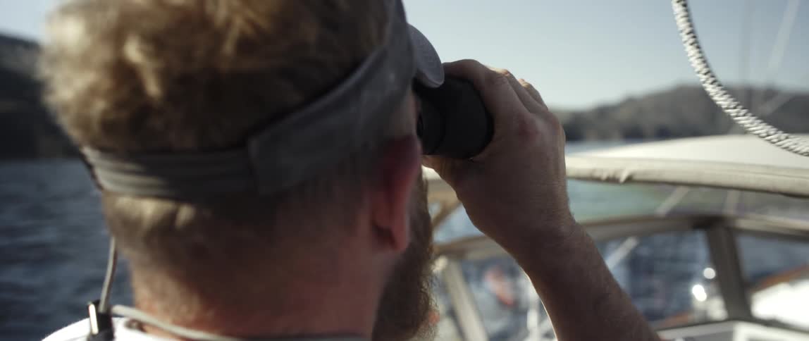 A man is using binoculars on a boat