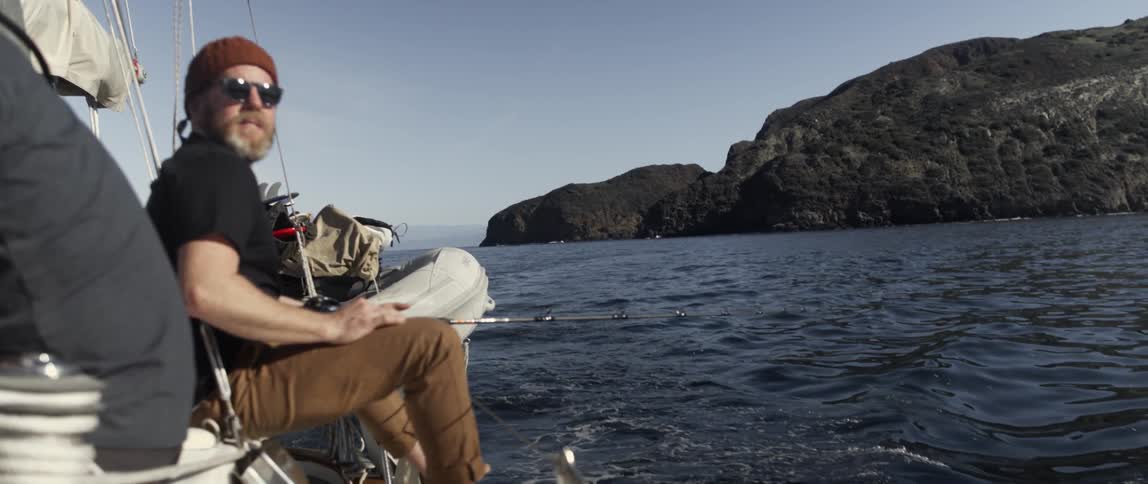 A man is fishing off the side of a boat