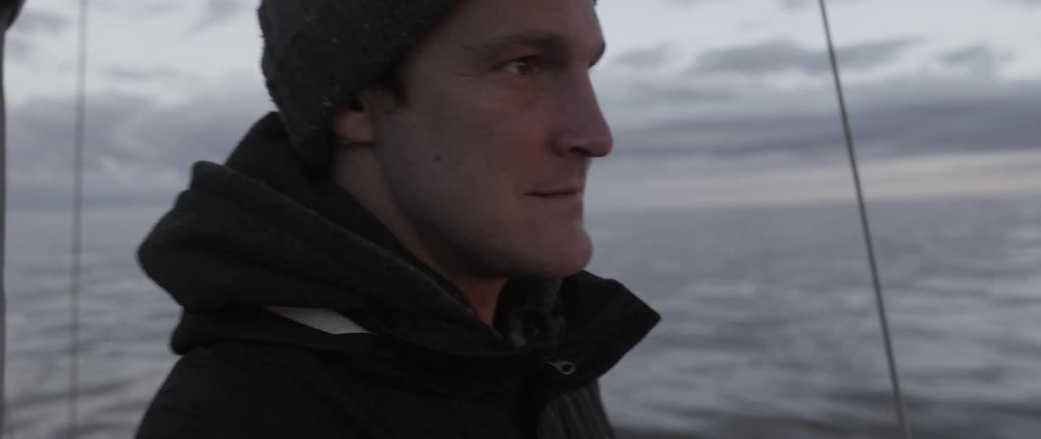 A man stands on a boat on a cloudy day