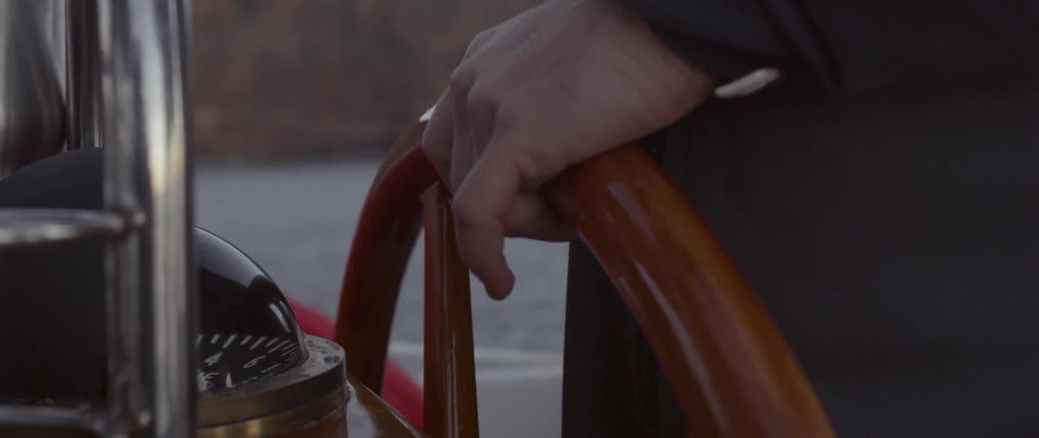 A person is steering a boat wheel