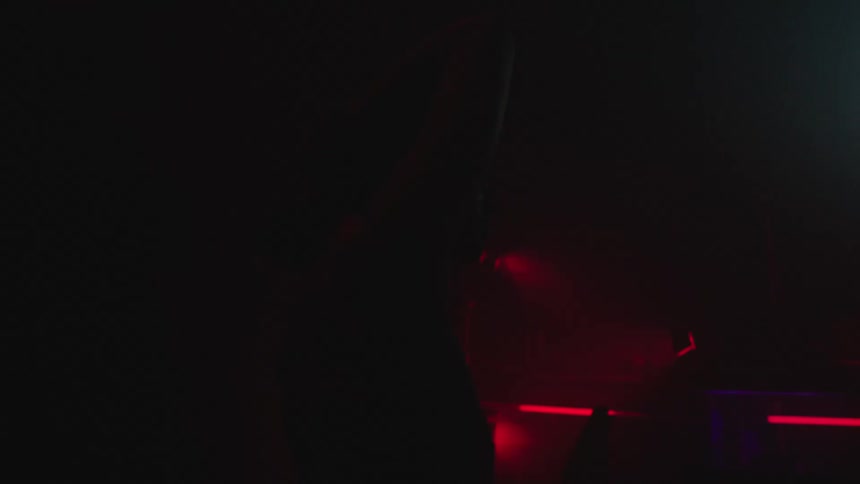 A young woman with her hands on her head dancing in a club environment