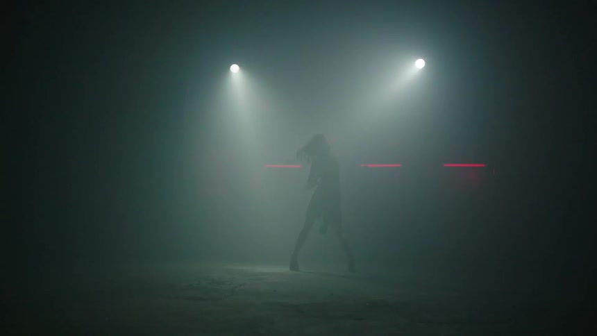 Person dancing in a dark indoor environment with flickering lights