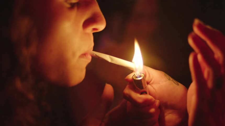Closeup of a woman with a cigarette in her mouth being lit by a lighter