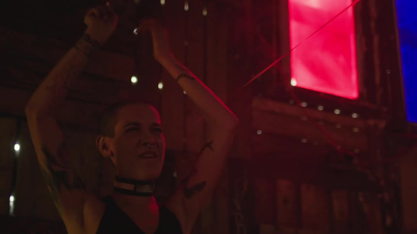 A woman with short hair holding a cigarette and singing while dancing and smiling