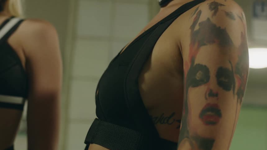 Tattooed woman standing up next to two other women indoors
