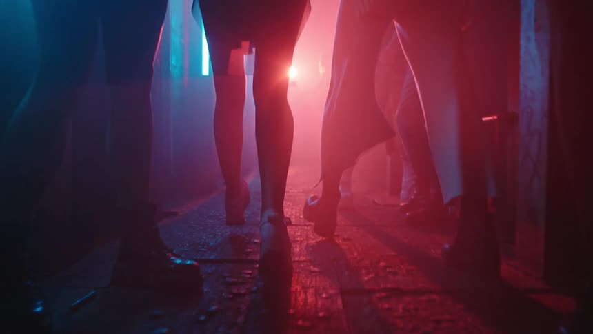 Two females walking out of a party while others are standing