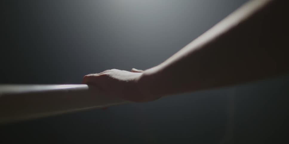 Close up of a human hand interacting with a handrail indoors under a spotlight