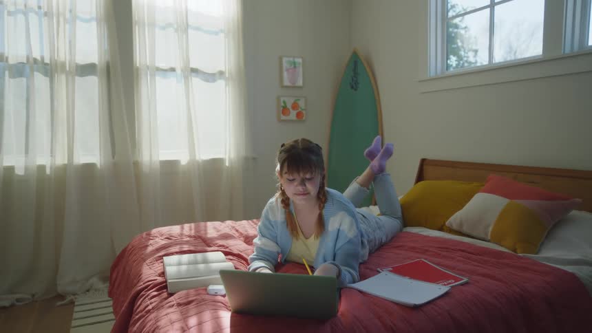 A girl lying on a bed and studying with a book and notebook