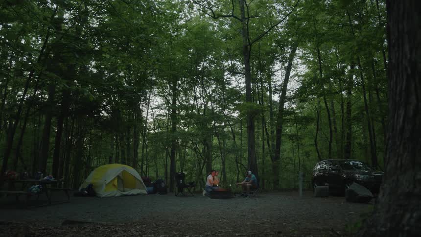 Three people are gathered around a campfire