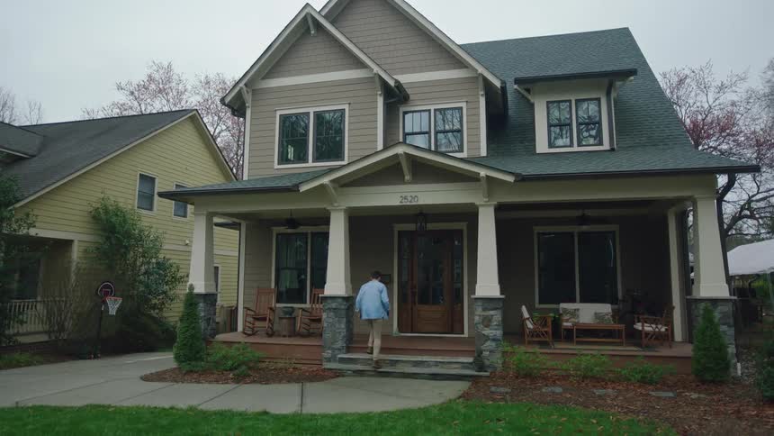 A man is walking to open the door to the house