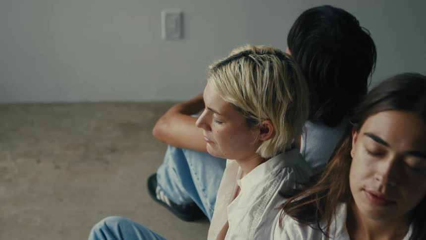 Three women meditate in a softly lit loft