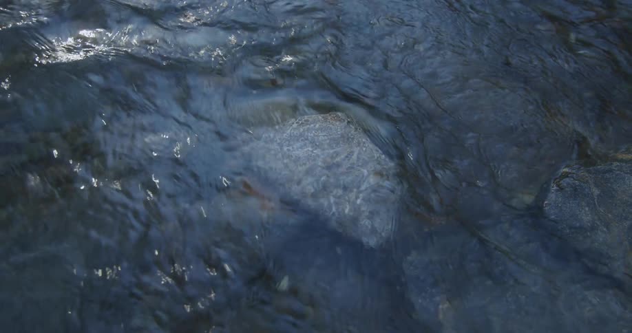 A stream of water flowing down the rock as the sun reflect on it