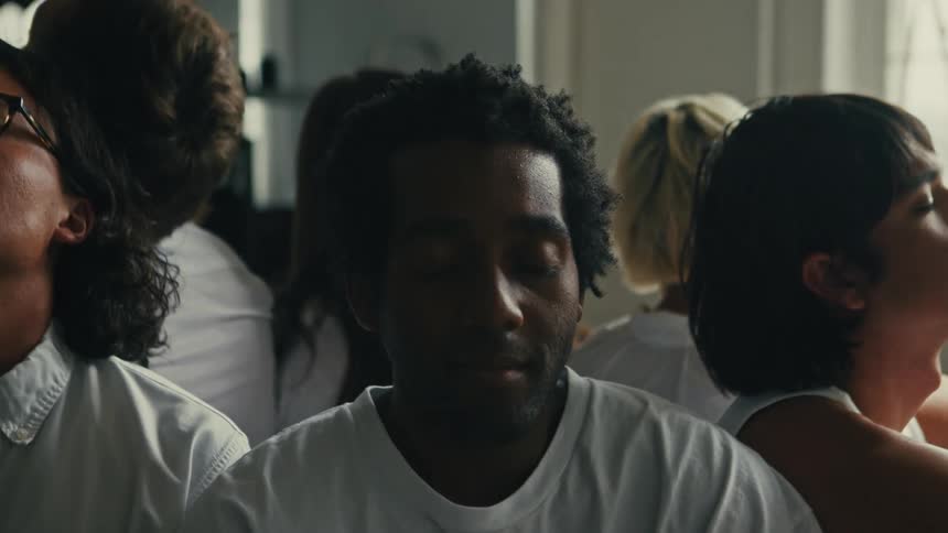 A group of people of black skin colors are sitting with their backs to each other and eyes closed