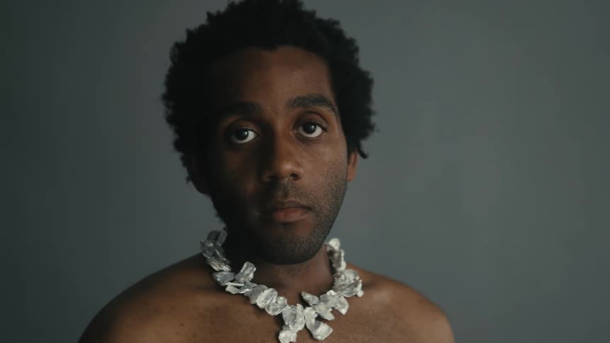 Shirtless man posing indoors wearing a necklace