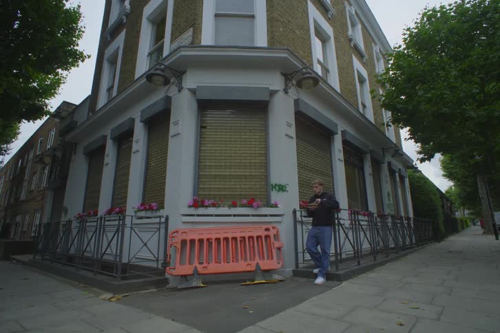 A man is eating on a West London street corners