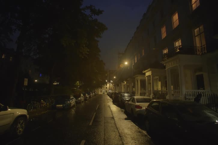A street with several cars parked on either side at night