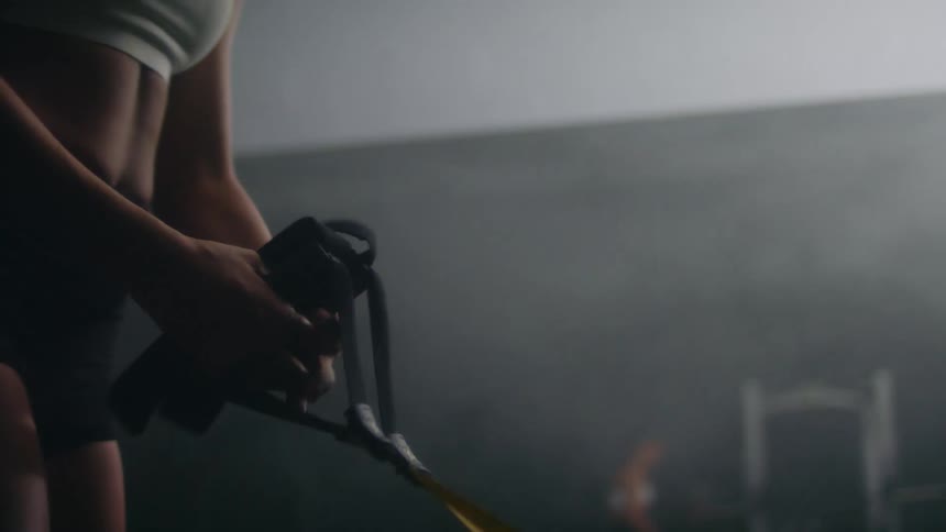 Close up of a woman holding trx bands in her hand while working out in the gym