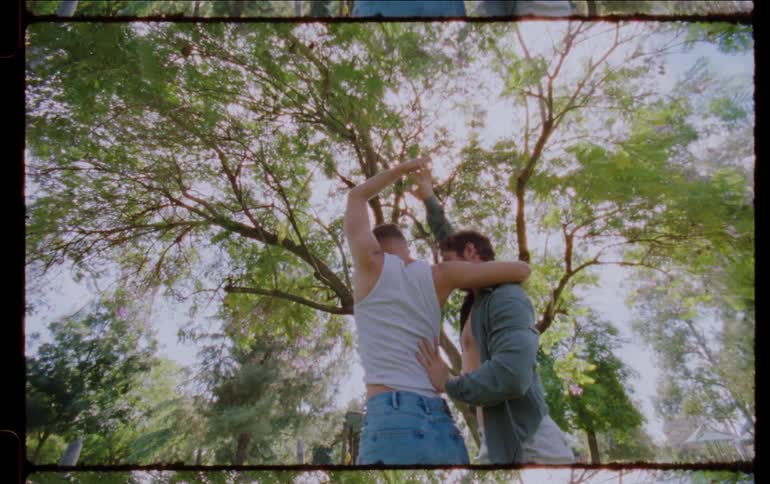 Two young dancers dance in a park full of people during the day