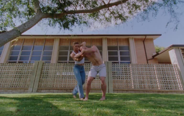 Two men dancing with physical contact in an outdoor environment