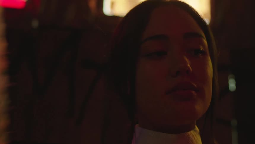 Portrait of a young woman in a dimly lit environment swaying a fan