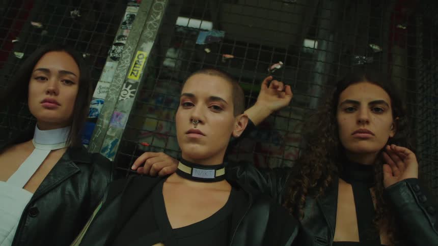 Three women stand shoulder to shoulder and look forward