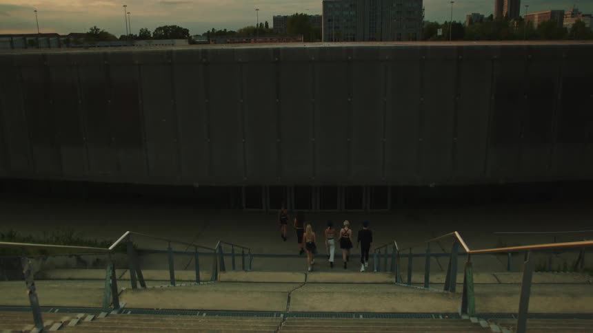 Small group of friends walking downstairs in an urban area during dusk or dawn