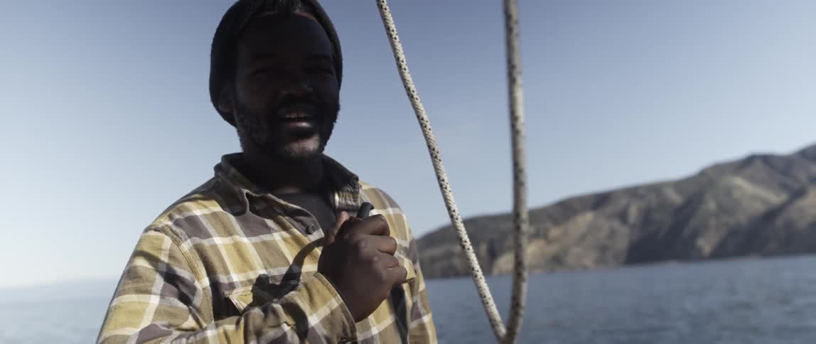 A man is holding a pipe talking on a boat
