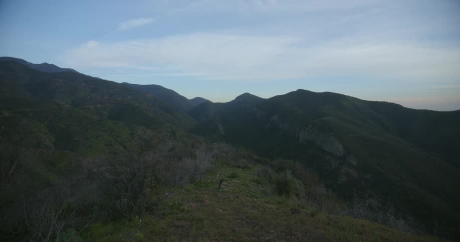 A mountain landscape with a path through grass up the slope
