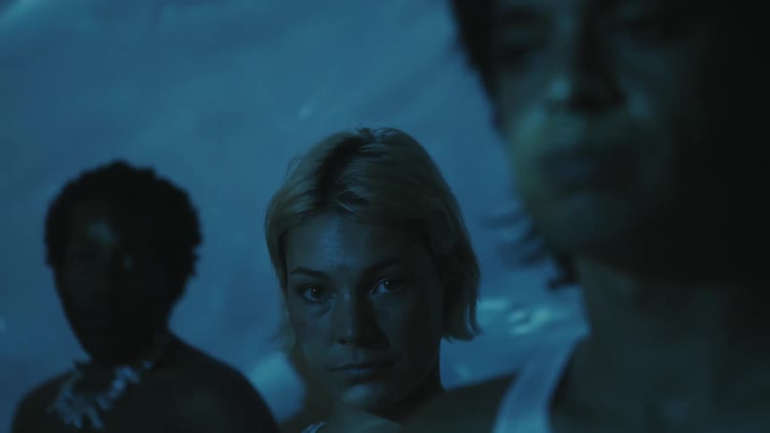 Three young adults indoors gaze at the camera while light dances across their face