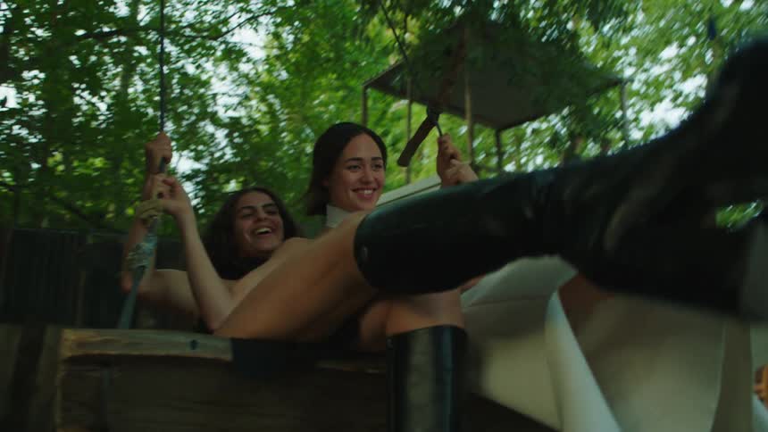 Two women are having fun playing on a swing outdoors