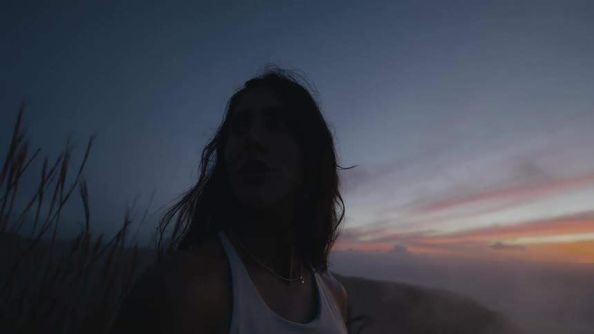 Close up of a woman standing outside in nature at dusk as fog settles in the valley