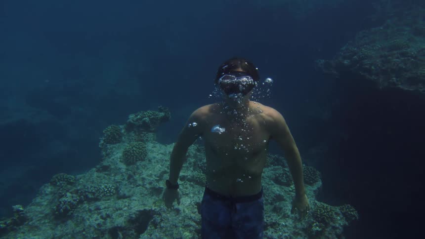 A diver swims towards the surface of the water