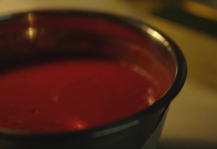 Hand stirs tomato sauce on a metallic bowl