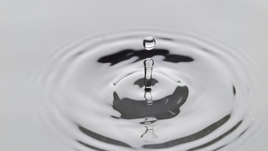 Water drop falls onto surface with splash