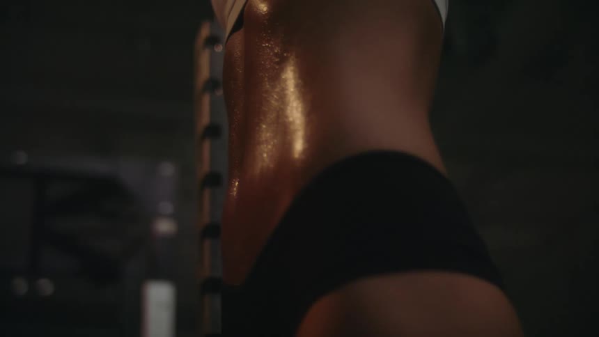 Sweaty athlete womans abs working out on the gym