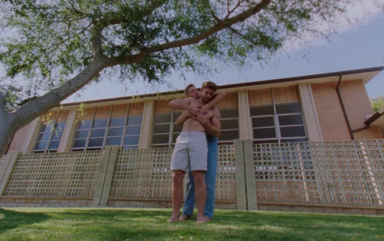 Two men hug and dance outside