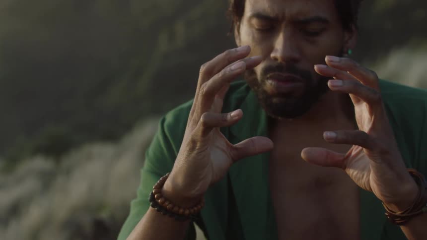 A man stands outside making intense hand gestures as a sign of worship