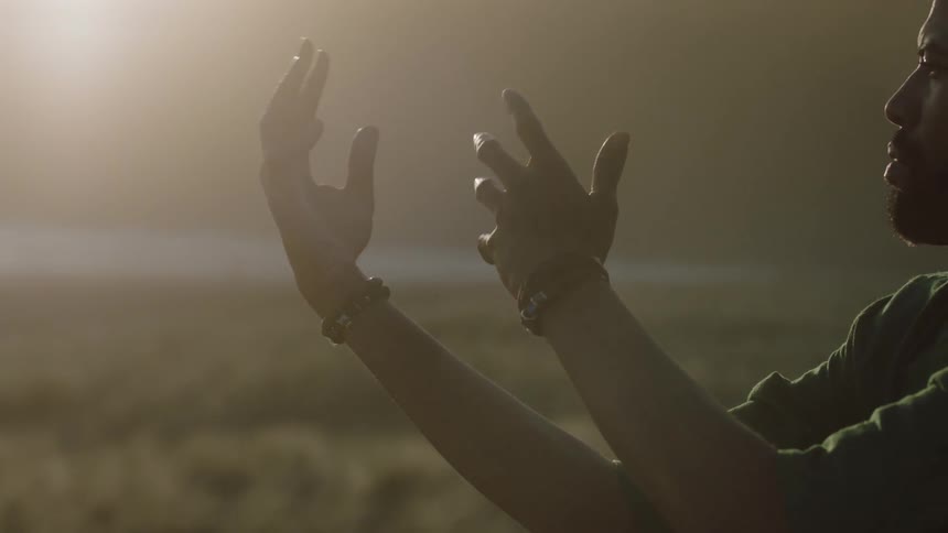 A black man moving his braceleted arms in a spiritual dance