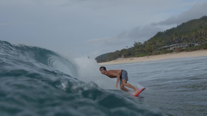 A man surfing a wave with a red colored board
