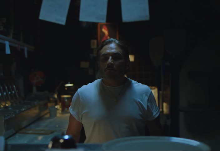 A black man hands another man a paper after answering a phone call in a bar