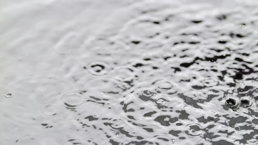 Lilltle water droplet as result from a splash are landing on the water causing small circular waves
