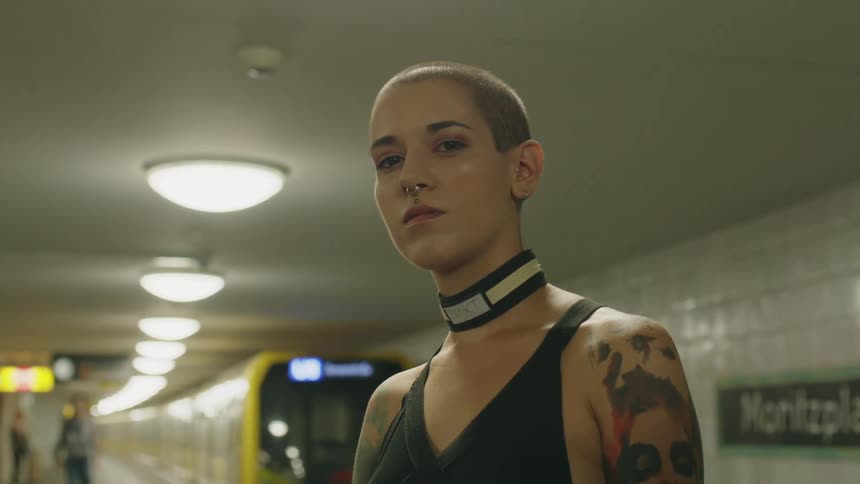 Portrait of a woman staring directly at the camera in an indoor subway environment