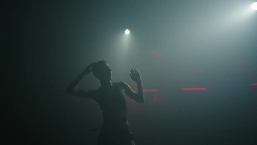A woman is dancing under the strobe lights
