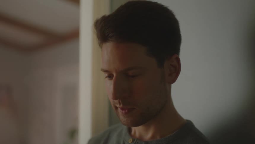 Man speaks to another person and hug while standing indoors