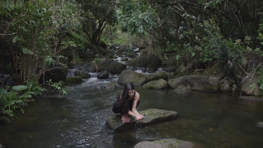 A woman washes her hands in the stream
